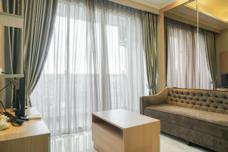 Soft beige sheer curtains with side drapes in a cozy sitting area